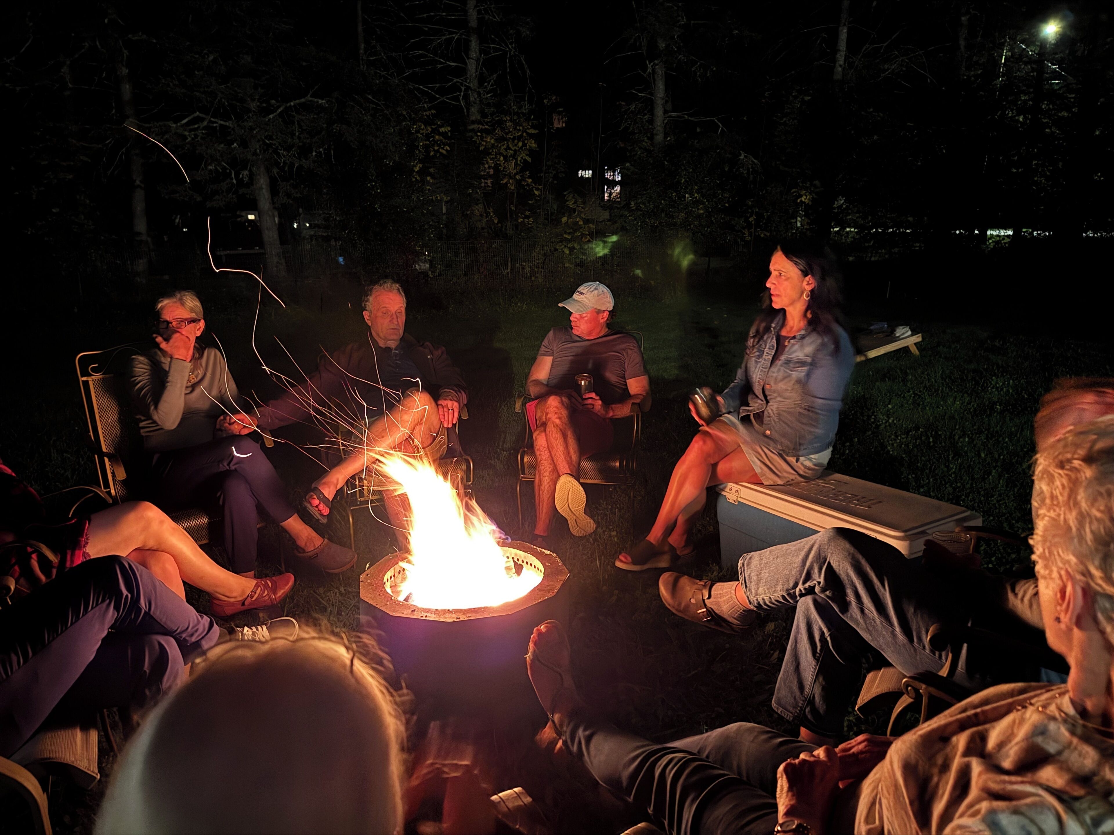 A group of people sitting around a campfire at night.