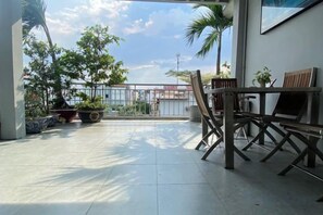 An outdoor patio with a table and chairs, potted plants, and a view of the cityscape.