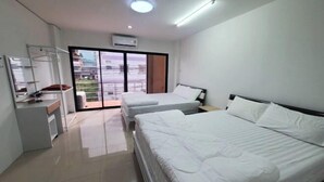 A modern hotel room with two beds, a desk, and a sliding glass door to the balcony. - Khoksametchun Hostel Plus 2 (Hat Yai)