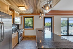 A modern kitchen with stainless steel appliances, wooden cabinets, and a large island with a sink. - Upscale 2-bedroom luxury loft in vibrant downtown Columbia, MO, in The District (Columbia)