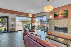 A spacious living area with a leather sofa, a fireplace, and large windows offering a view of the outdoors. - Upscale 2-bedroom luxury loft in vibrant downtown Columbia, MO, in The District (Columbia)