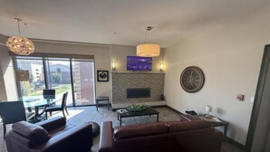 Una sala de estar moderna con chimenea, un ventanal grande y una zona de comedor.