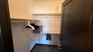 Un pasillo estrecho y pequeño con una puerta de madera a la derecha y un perchero con algunos ganchos a la izquierda.