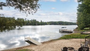 A lakeside beach with a dock, chairs, and a canoe. - Rennie Lake Hideaway (Traverse City)