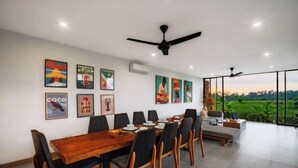 A dining area with a wooden table, black chairs, ceiling fans, and artwork on the walls. - Villa Eden by BaliSuperHost (Bali)