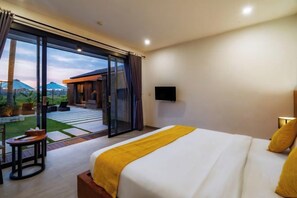 A bedroom with a bed, a TV, and a sliding glass door leading to an outdoor patio. - Villa Eden by BaliSuperHost (Bali)