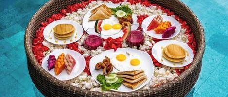 A round wicker basket filled with various food items placed on a poolside.