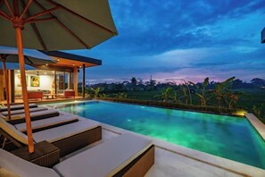 A swimming pool with lounge chairs and an umbrella, surrounded by a lush landscape. - Villa Eden by BaliSuperHost (Bali)