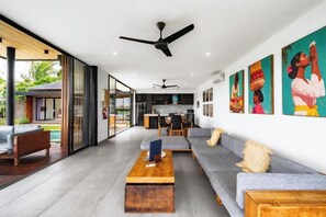 A modern living room with a sofa, coffee table, and a view into the kitchen. - Villa Eden by BaliSuperHost (Bali)