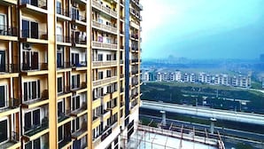 A multi-story residential building with balconies, a view of a highway, and surrounding urban landscape. - Anantya Inn (Greater Noida)