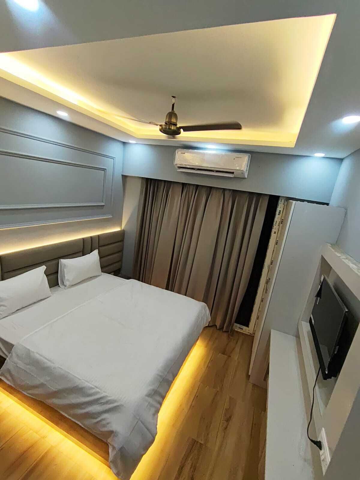 Een moderne hotelkamer met een bed, plafondventilator, airconditioning en een televisie.
