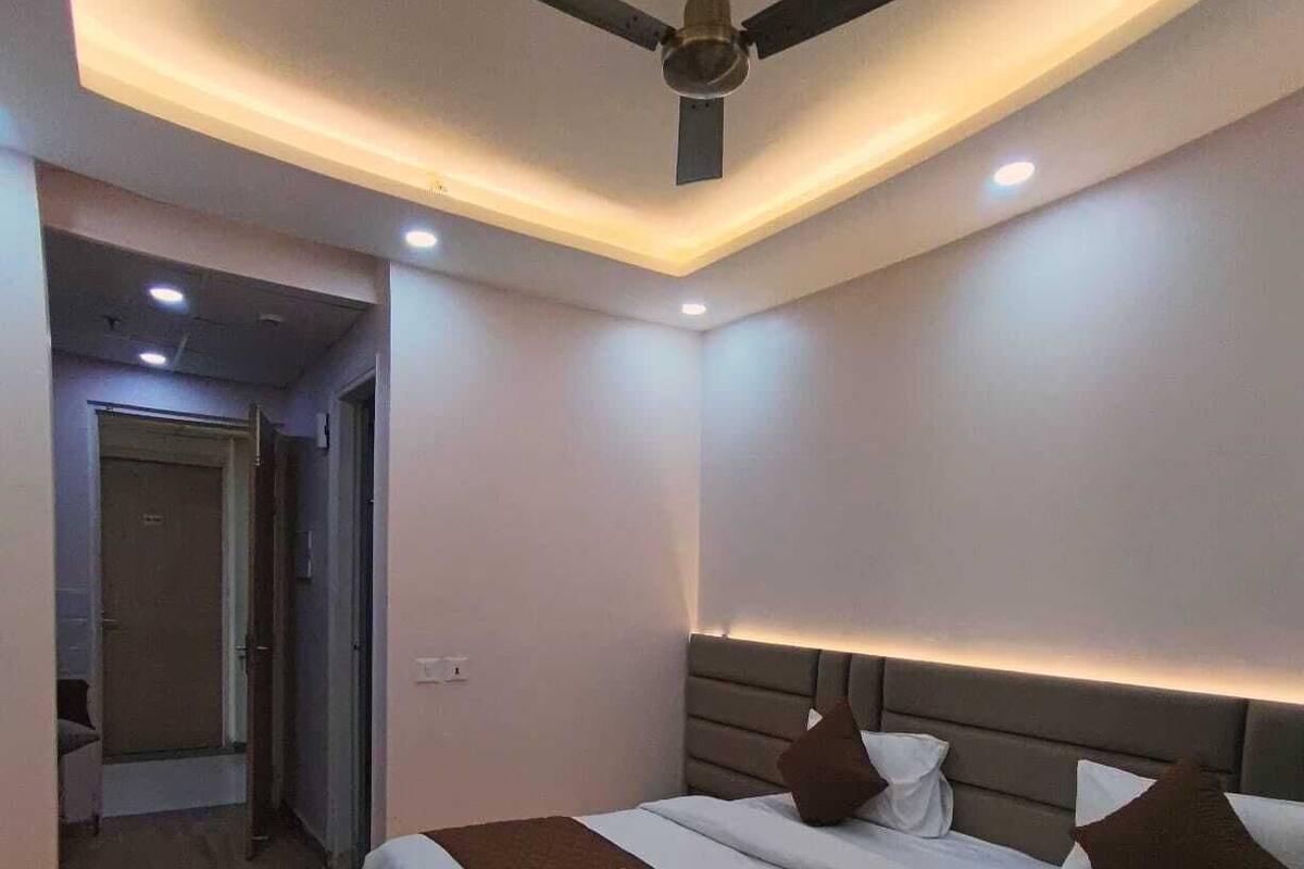 Ein modernes Hotelzimmer mit einem großen Bett, einem Deckenventilator, eingelassener Beleuchtung und Holzboden.