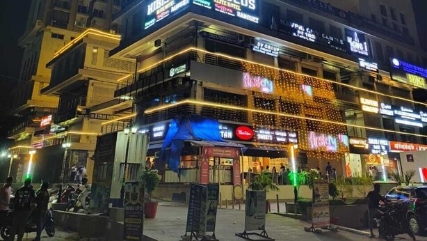 A multi-story hotel with illuminated signage, including "HIBISCUS" and "ELITE HOTEL." - Anantya Inn (Greater Noida)