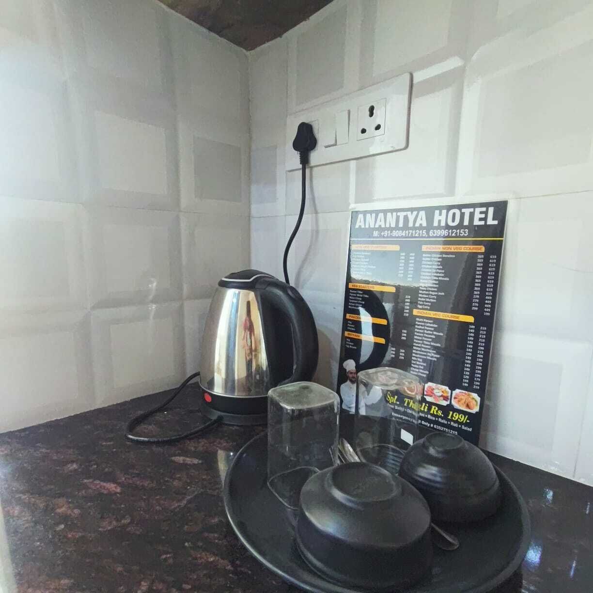 A kitchen counter with a kettle, a glass, and a menu for Anantya Hotel.