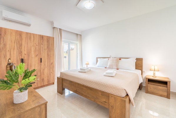 A bedroom with a wooden bed, bedside tables, a potted plant, and a window with curtains.