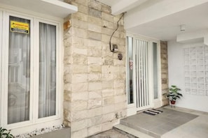 Fachada de piedra con una puerta, una ventana y un letrero, además de una maceta con planta.