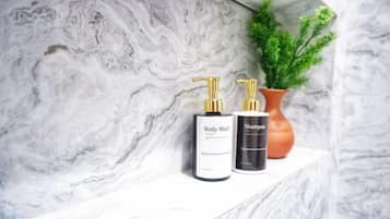 A marble shelf with two bottles of body wash and shampoo.
