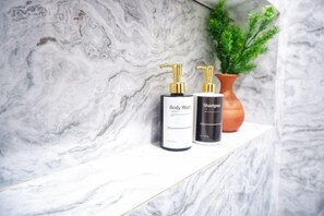 Estante de mármol con dos botellas de gel de baño y champú.