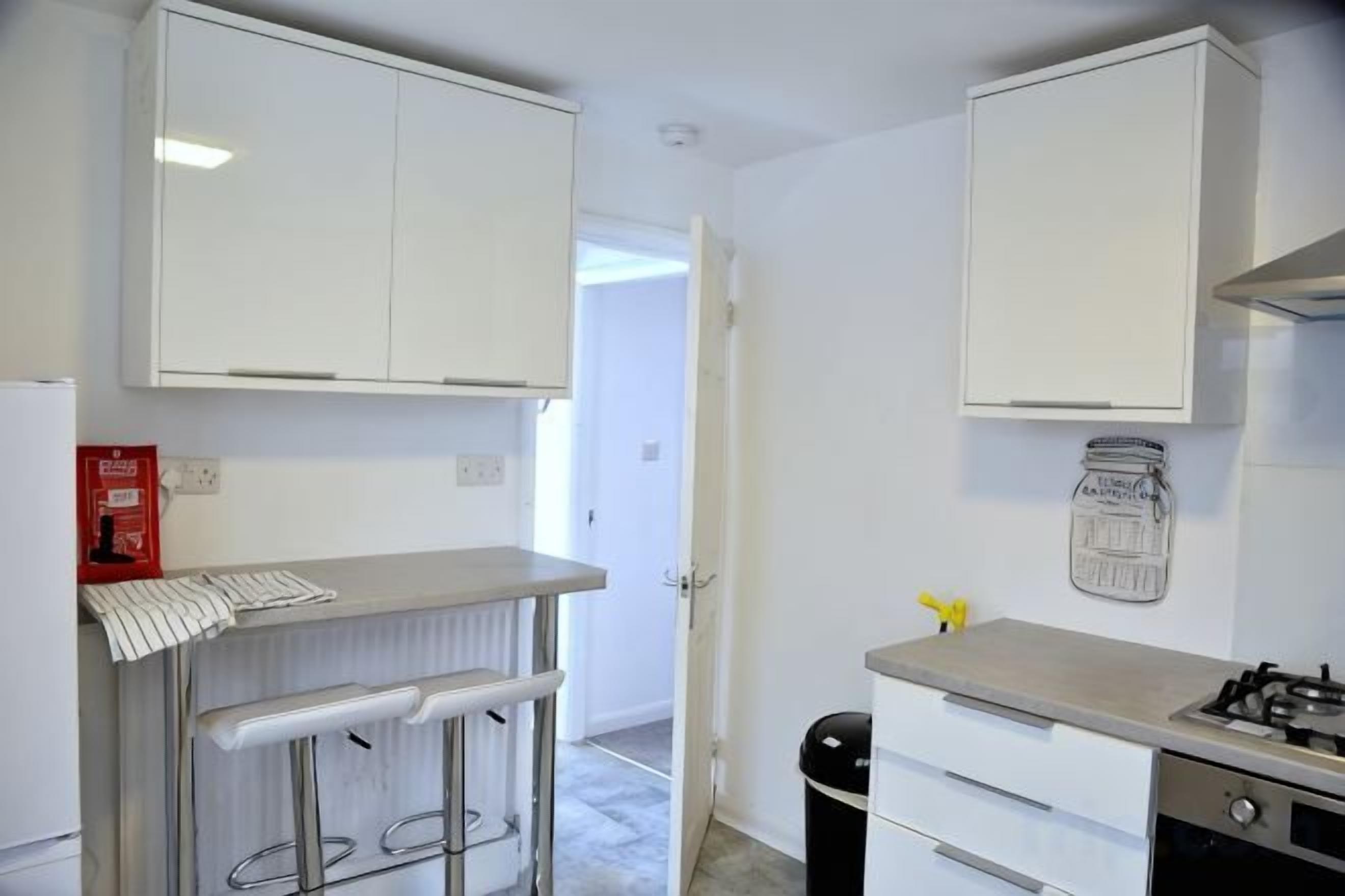 A compact kitchen with white cabinets, a countertop, and a gas stove.