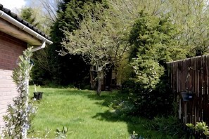 A backyard with a grassy lawn, a wooden fence, and a brick building. - Lindrick Villa Peaceful 3Bd Bungalow Parking (Leicester)