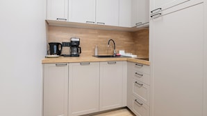 A modern kitchen with light-colored cabinets, a wooden countertop, a coffee maker, and a sink. - RentPlanet - Apartament Rondo ONZ (Warsaw)