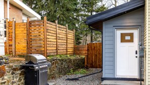 A backyard with a barbecue grill, a wooden fence, and a small shed. - 2 Bedrooms l  Sleeps 4 Adults l Kitchenette (Fernie)
