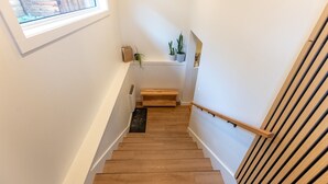 A wooden staircase with a handrail, a small bench, and potted plants on the landing. - 2 Bedrooms l  Sleeps 4 Adults l Kitchenette (Fernie)