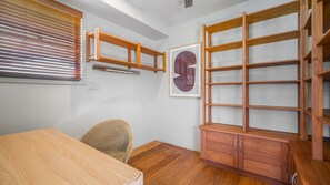 Een kamer met een houten tafel, een stoel, een houten kast en een wandplank.