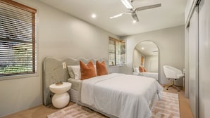 A bedroom with a bed, bedside tables, a ceiling fan, and a large mirror.