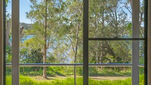 A window view of a natural landscape with trees and a body of water.