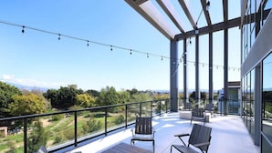 A spacious balcony with a wooden table and chairs, overlooking a scenic landscape. - Luxe Deco Haven Pool Gym Parking Close to Disneyland (Santa Ana)