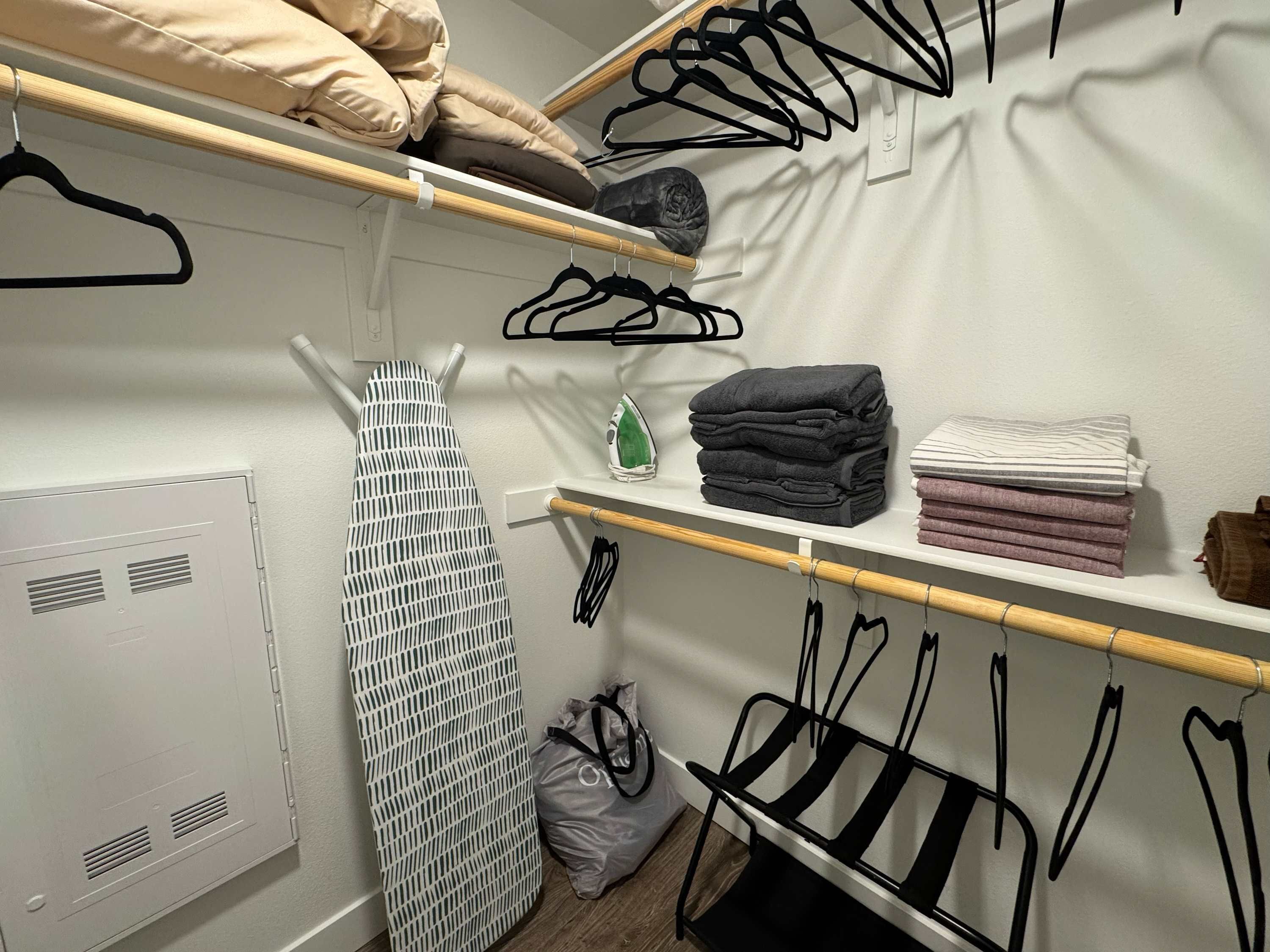Un placard bien rangé, avec des étagères où sont pliés les vêtements, une tringle pour suspendre les vêtements et un tableau blanc avec un quadrillage.