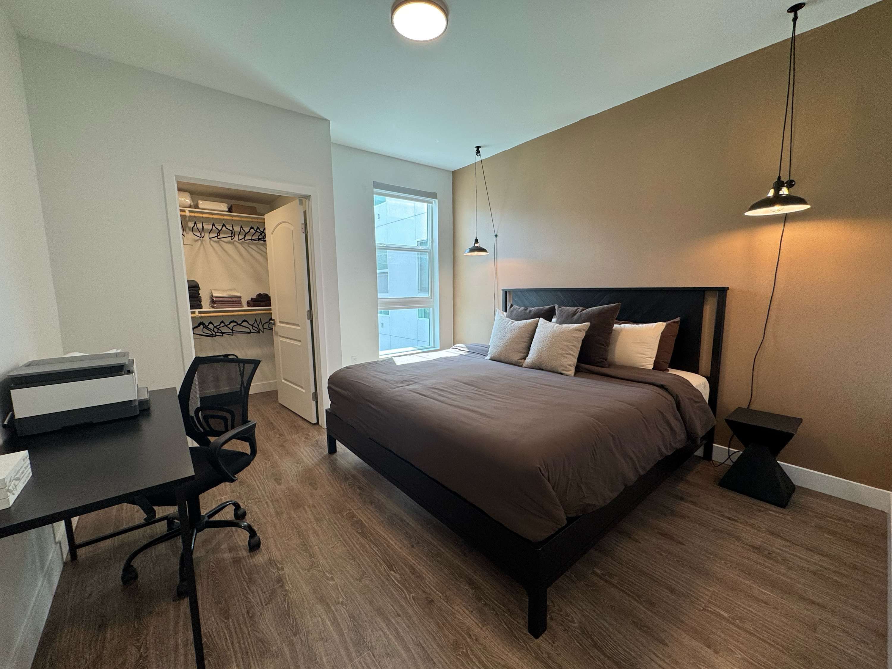 A bedroom with a bed, desk, chair, and a closet.
