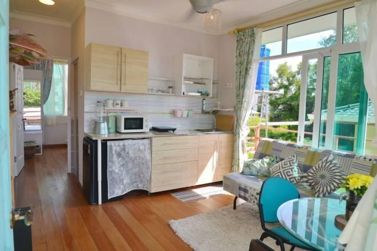 A compact kitchen with wooden cabinets, a microwave, and a small refrigerator.