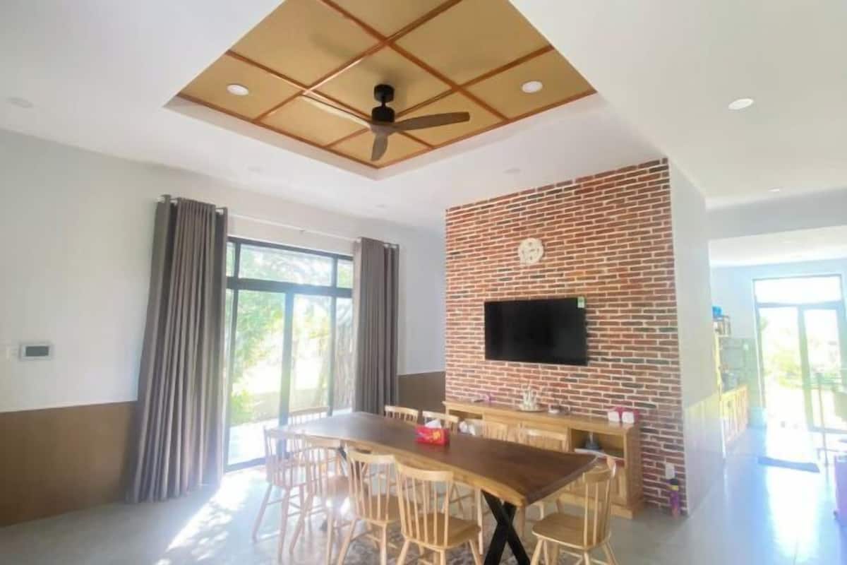 Ein Essbereich mit Backsteinwand, Deckenventilator und an der Wand befestigtem Flachbildfernseher.
