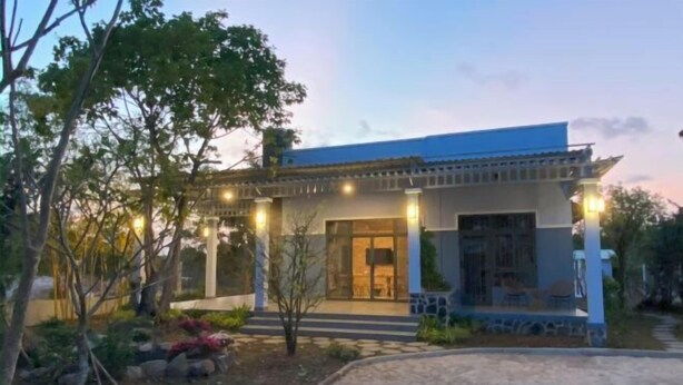 A modern building with a covered entrance, outdoor seating, and a landscaped garden. - MyGarden Villa Binh Chau Hotspring (Binh Chau)