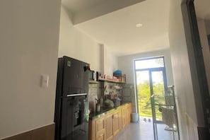 A modern kitchen with a refrigerator, wooden cabinets, and a glass countertop.