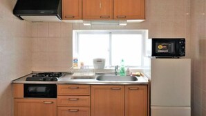 Una cocina con armarios de madera, estufa a gas, microondas y refrigerador.