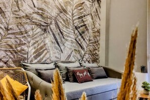A living room with a sofa, cushions, and a patterned wall. - Elpis' cozy & luxury apartment (West Athens)