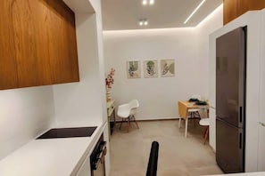 Een praktische keuken met een koelkast, een eettafel met stoelen en een klein barretje.