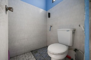 A small bathroom with a toilet, a blue wall, and patterned floor tiles.