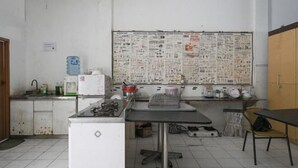 A kitchen with a refrigerator, sink, and a bulletin board filled with papers. - Bunk Bed Bali near Sanur Mitra RedDoorz (Bali)