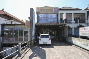 Un edificio con un coche estacionado adelante, un cartel y una entrada con portón.