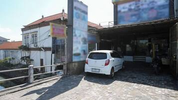 A white car parked in front of a building with a tiled roof and a signboard.