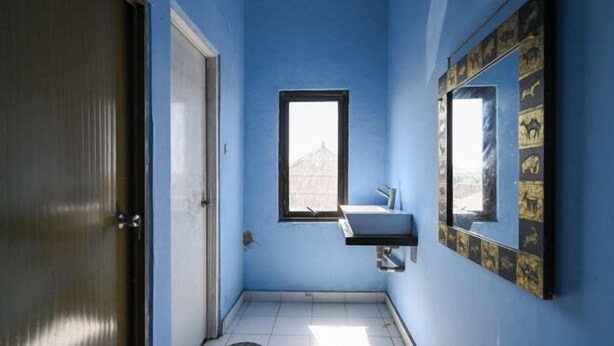 A bathroom with a blue wall, a window, a sink, and a door. - Bunk Bed Bali near Sanur Mitra RedDoorz (Bali)