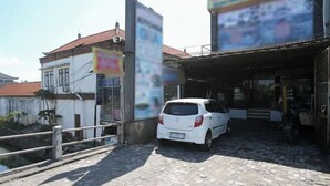 A white car parked in front of a building with a tiled roof and a signboard. - Bunk Bed Bali near Sanur Mitra RedDoorz (Bali)