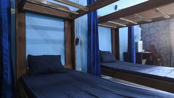 A bunk bed room with a wooden frame, a single bed, and a small table.
