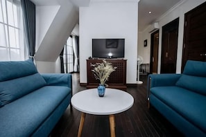 Ein modernes Wohnzimmer mit zwei blauen Sofas, einem weißen Couchtisch und einem Fernseher auf einer Holzkommode.