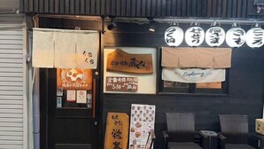 Entrada de un restaurante con un letrero de madera, un cartel de menú y algunas sillas afuera.