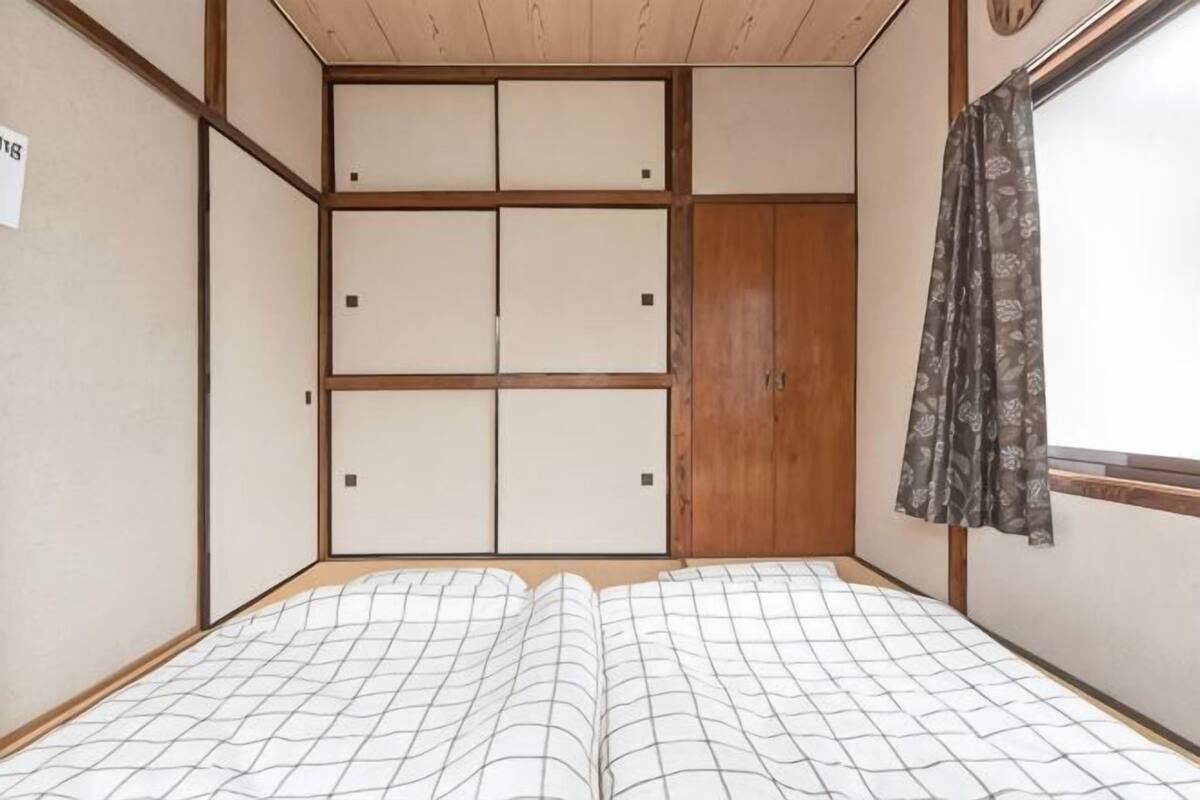 Une pièce avec un lit, une armoire en bois et une fenêtre avec un rideau.